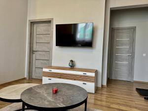 a living room with a table and a tv on a wall at DB Guest House 2 in Târgu Secuiesc +6 photos