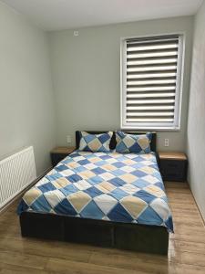 a bedroom with a blue and white bed with a window at DB Guest House 2 in Târgu Secuiesc