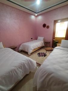a bedroom with two beds and a pink wall at Nomad Surf Morocco in Imsouane