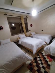 a room with three beds and a window at Nomad Surf Morocco in Imsouane