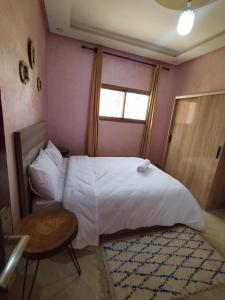 a bedroom with a bed and a table and a window at Nomad Surf Morocco in Imsouane +6 photos