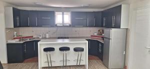 a kitchen with blue cabinets and a counter with stools at Vila Marjanovic PN in Paraćin
