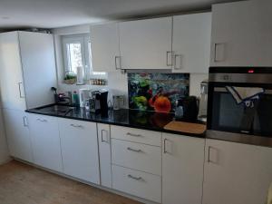 a kitchen with white cabinets and a black counter top at FeWo Eriswil by R&B in Eriswil