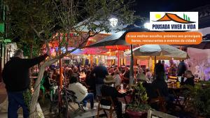 a crowd of people sitting at an outdoor restaurant at night at Ninho do Vale - Centro Conservatória in Conservatória +62 photos