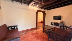 a living room with a couch and a tv at Coastal Hideout Family Cottages Malpe Beach in Malpe
