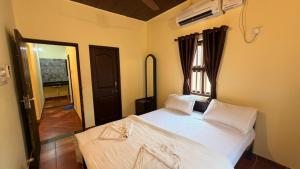 a bedroom with a bed with white sheets and a window at Coastal Hideout Family Cottages Malpe Beach in Malpe