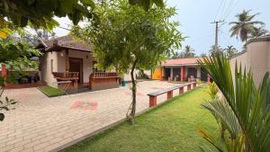 a house with a patio and a yard with a tree at Coastal Hideout Family Cottages Malpe Beach in Malpe