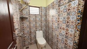 a bathroom with a toilet and a tiled wall at Coastal Hideout Family Cottages Malpe Beach in Malpe +36 photos
