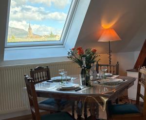 a table with a vase of flowers and a window at Gîte le Nid in Uffholtz
