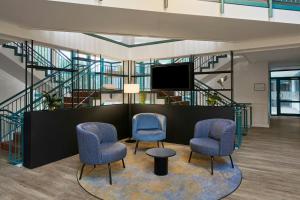 a waiting room with two chairs and a tv at Four Points Flex by Sheraton Hannover in Hannover