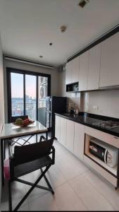 a kitchen with white cabinets and a table and a table and a chair at The Base Central Pattaya in Pattaya