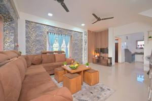 a living room with a brown couch and a table at ll EMPYREAN STAY ll THE LOVE SHAKE ll 2BHK ll AC ll PRIVATE POOL ll BACHELORS FRIENDLY ll in Malavli