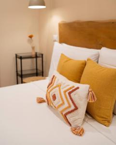 a bed with white sheets and yellow pillows at Guest house IL VICOLO in Caprarola
