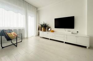 a living room with a television on a white cabinet at Thomas House on Train Tracks in Mestre