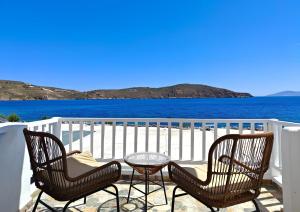 two chairs and a table on a balcony overlooking the water at Liva Mare - Serifos in Livadakia