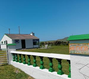 a white house with a green railing next to a yard at An Tigín, Gortadoo in Dingle +4 photos