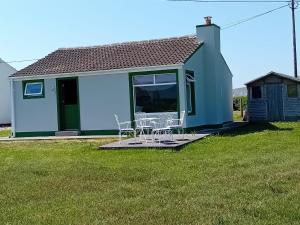 a blue house with chairs on a lawn at An Tigín, Gortadoo in Dingle