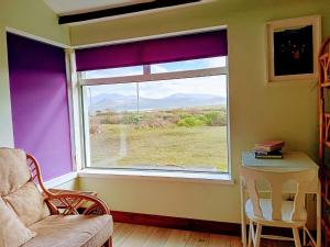 a window in a room with a chair and a table at An Tigín, Gortadoo in Dingle