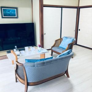 a living room with a couch and chairs and a tv at 福のや in Unnan