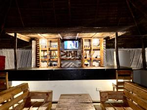 Ein Raum mit einer Bar mit Bänken und einem Fernseher in der Unterkunft Dindini in Kilindoni