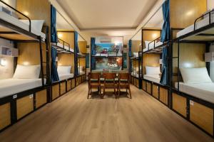 a room with several bunk beds with a table and chairs at Hanoi Oldtown Nomad Hostel & Pub in Hanoi