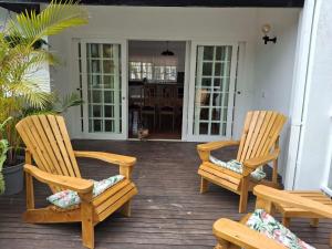 two wooden chairs and a table on a porch at Sensitively restored spacious apartment in Durban