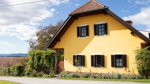 a yellow house with black shuttered windows at Traussegghof Ferienhaus Familie Uhl in Tanzelsdorf