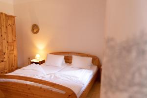 a bedroom with a wooden bed with white sheets and pillows at Traussegghof Ferienhaus Familie Uhl in Tanzelsdorf