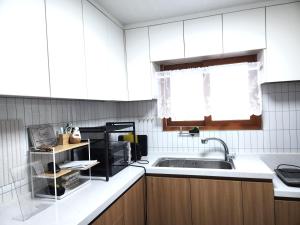 a kitchen with white cabinets and a sink and a window at Hanyang Healing House - 외국인 전용 in Seoul