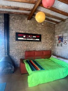 a bedroom with a green bed in a stone wall at GinTonic Rancho in San Luis