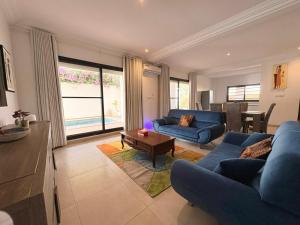 a living room with a blue couch and a table at Villa Le Charme de Somone Piscine privée confort & proximité plage in Somone
