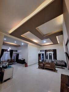 a large living room with a coffered ceiling and chairs at Jomariz Homestay in Labuan Bajo