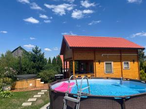 a house with a swimming pool in front of it at Domek u Emi jakuzzi Wilkasy Giżycko in Wilkasy