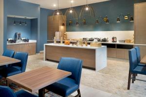 a restaurant with blue chairs and tables and a kitchen at SpringHill Suites by Marriott Locust Grove in Locust Grove