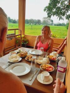 a woman sitting at a table with food on it at Paddy Wind Eco Lodge Sigiriya in Kibissa +38 photos