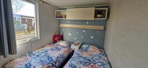 two beds in a small room with a window at Chalet B2 900 m vom Strand in Koudekerke