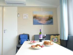 a table with a bottle of wine and a plate of food at Chalet B2 900 m vom Strand in Koudekerke +10 photos