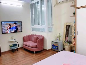 a living room with a pink chair and a tv at Ribi Home in Hà Ðông