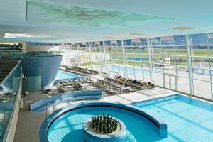 - une piscine intérieure dans un grand bâtiment avec des chaises dans l'établissement Apartpension Oberhauser, à Kaprun