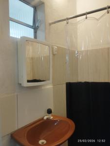 a bathroom with a sink and a tv on the wall at Quitinete 5 Itaguaí in Itaguaí