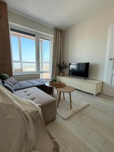 a living room with a couch and a tv at Bird's eye Apartment with sea view 18th floor in Klaipėda