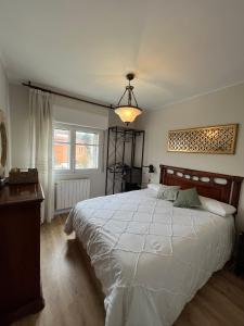 a bedroom with a large white bed and a chandelier at Balcón del cubo in Covaleda