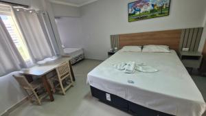 a bedroom with a large bed and a table and chairs at Araras Apart Service in Caldas Novas