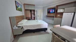 a small bedroom with a bed and a refrigerator at Araras Apart Service in Caldas Novas +7 photos