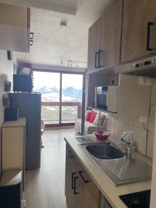 a kitchen with a sink and a living room at Studio montagne in Villarembert