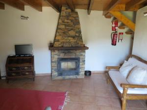 a living room with a fireplace and a couch at Casa das Oliveiras in Colmeal