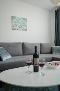 a bottle of wine and two glasses on a table at SK Blue apartment in Lukavica