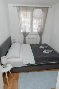a large bed in a room with two windows at SK Blue apartment in Lukavica