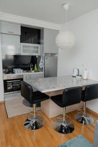 a kitchen with a table and four bar chairs at SK Blue apartment in Lukavica