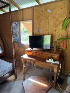 a living room with a tv on a wooden table at Rasta Rustic Off Grid Cabin in Gros Islet +2 photos